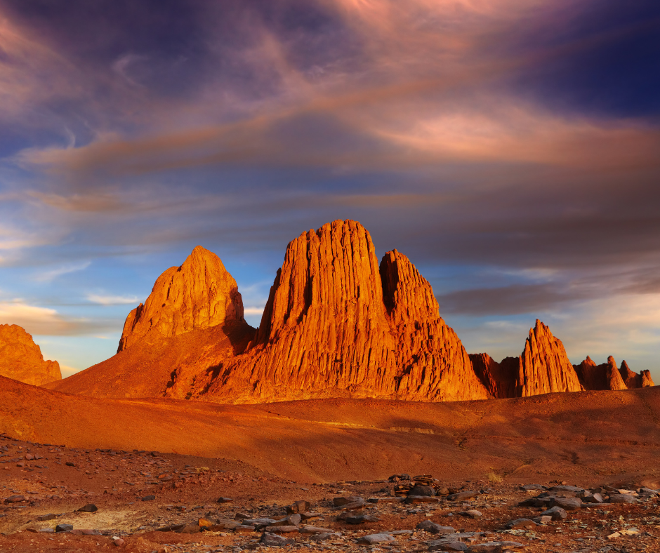 Jagged red rock peaks in the Hoggar Mountains under a dramatic sunset sky