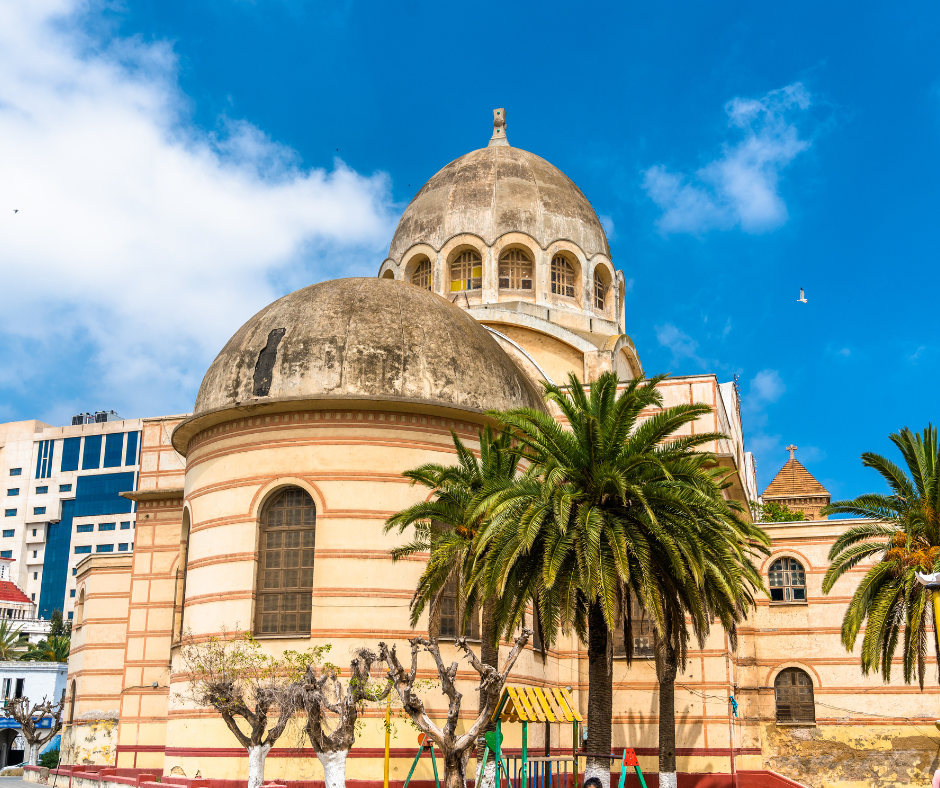 Domed Sacré-Coeur Cathedral in Oran, now a library, with palm trees and blue sky