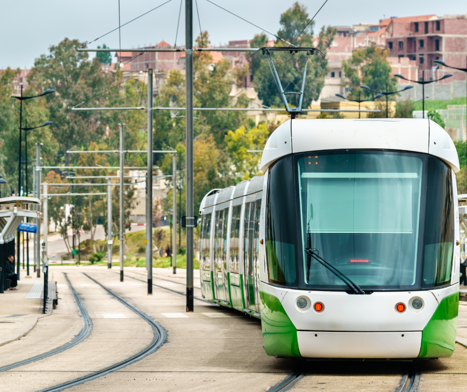 Green and white Constantine tram running along a tree-lined track