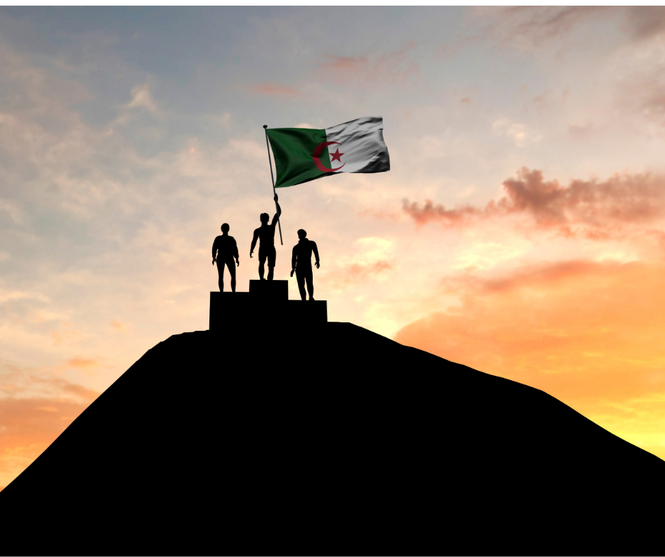 Silhouettes of three figures on a podium raising an Algerian flag at sunset