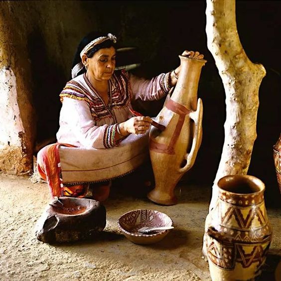 Kabyle woman in traditional dress painting clay pottery