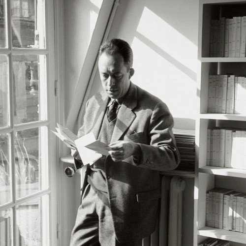 Albert Camus reading a letter by a window, black and white portrait