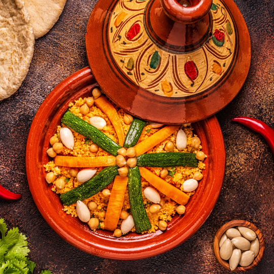 Couscous with vegetables, chickpeas and almonds in a painted clay tagine