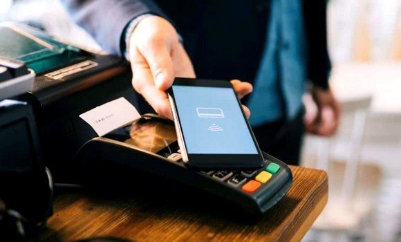 Customer paying by tapping a smartphone on a card payment terminal