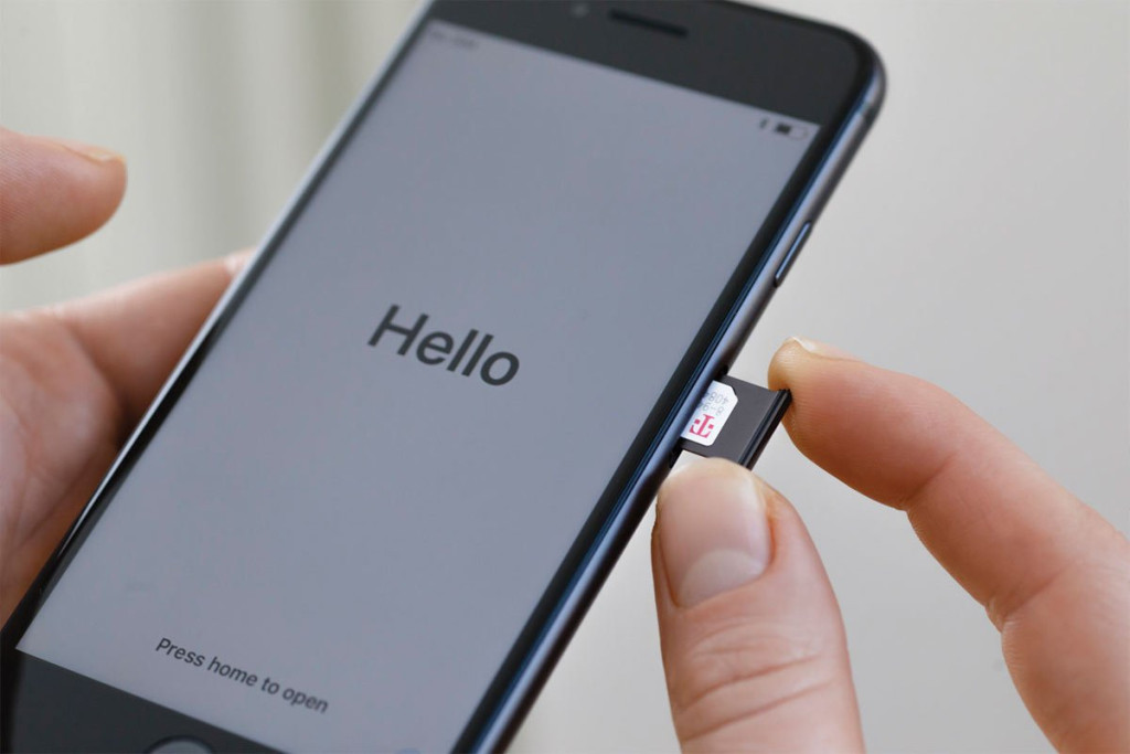 Hand inserting a SIM card tray into a smartphone