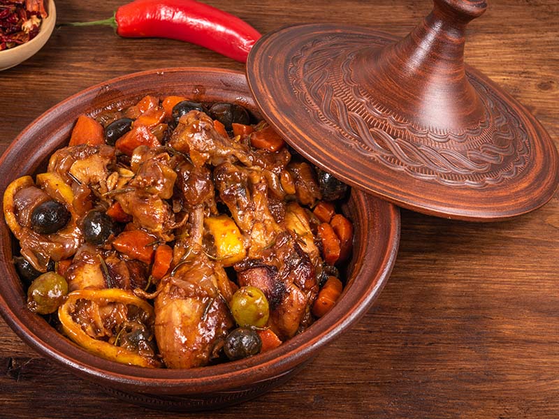 Clay tajine of chicken stewed with green olives, carrots and peppers