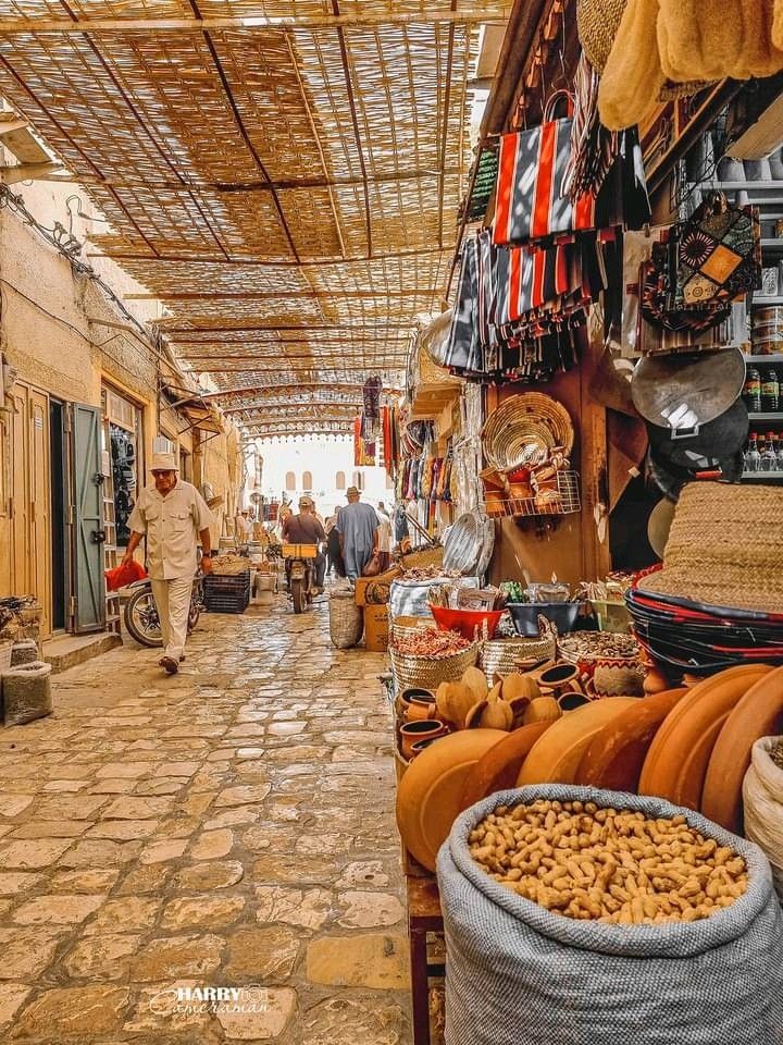 Covered market lane with baskets, pottery, rugs and sacks of peanuts