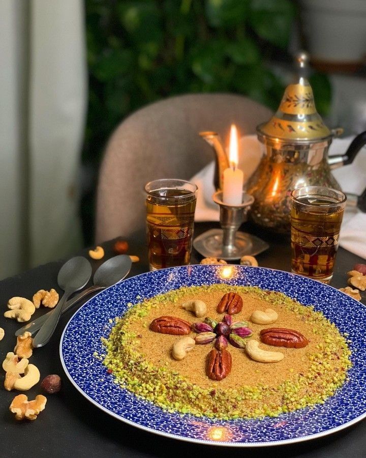 Semolina dessert topped with pecans and cashews, served with glasses of tea by candlelight