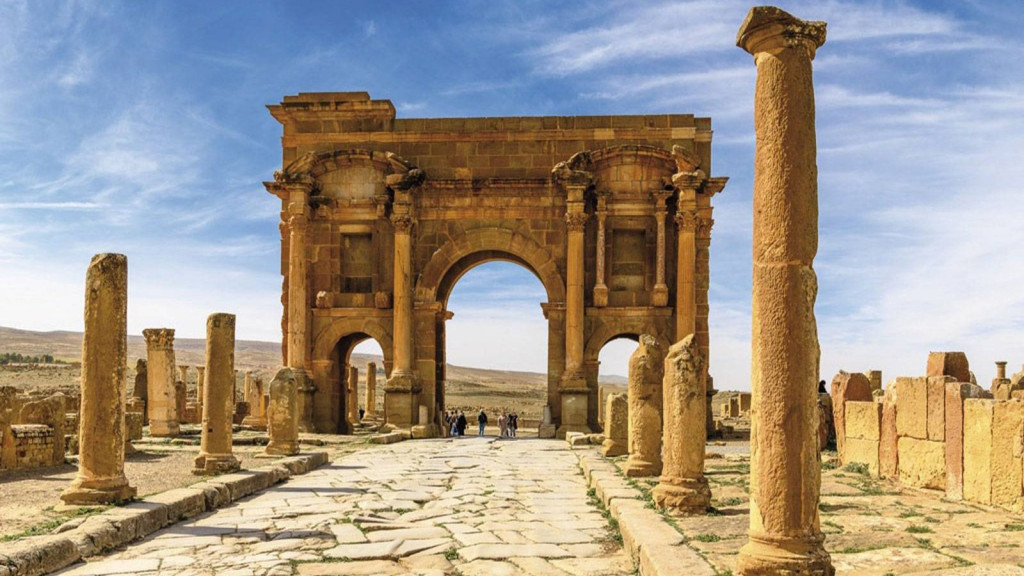 Roman arch of Trajan at Timgad framed by fallen columns