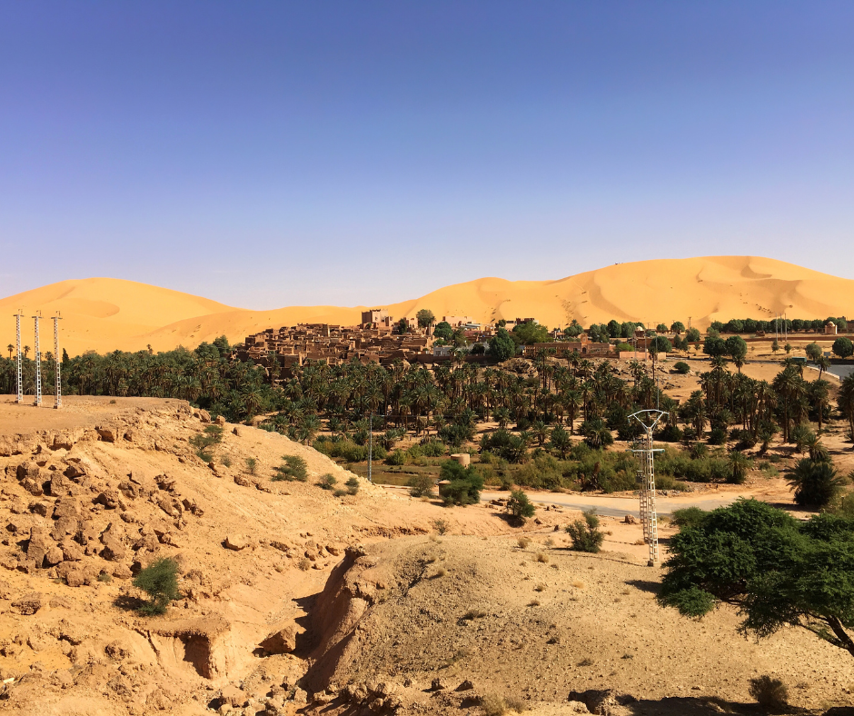 Ksar and palm grove of Taghit below tall orange sand dunes