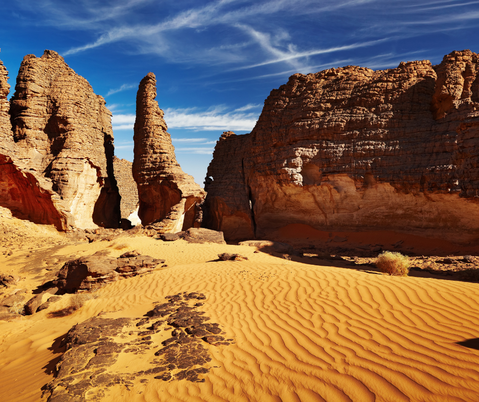 Sandstone rock towers rising from golden dunes in the Tassili n'Ajjer