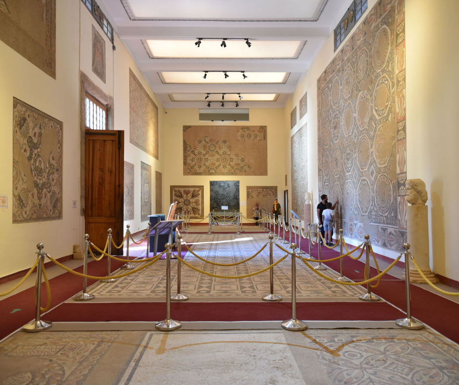 Museum hall at Timgad with large Roman mosaics on walls and floor behind rope barriers