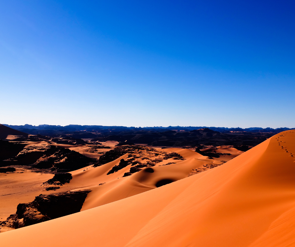 Orange dune crest above dark rock outcrops in the Tassili n'Ajjer desert