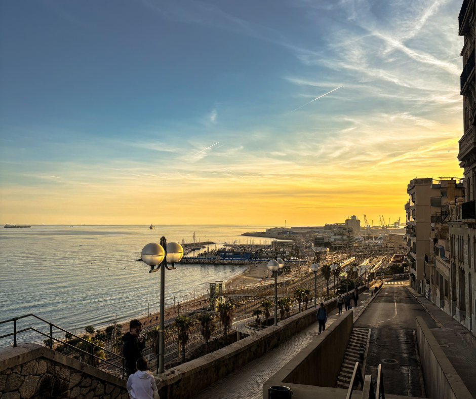 Seafront staircase and promenade overlooking a harbor at sunset