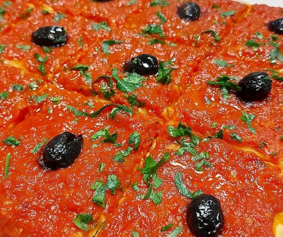 Pizza carrée squares covered in tomato sauce, black olives and parsley