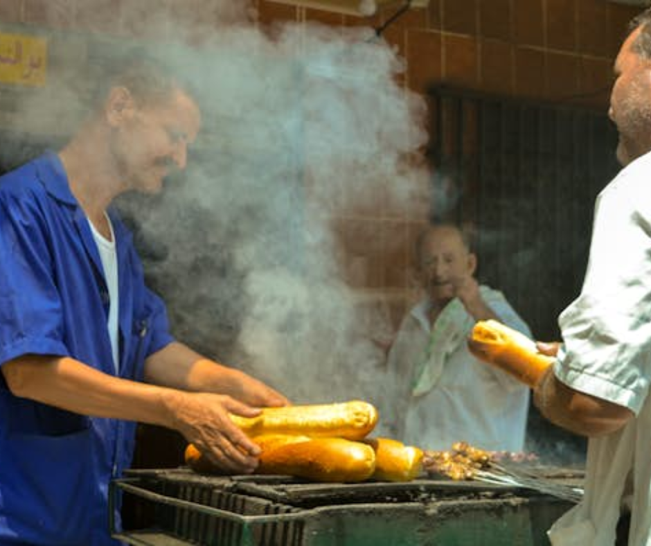 Street vendors grilling bread loaves over charcoal in thick smoke