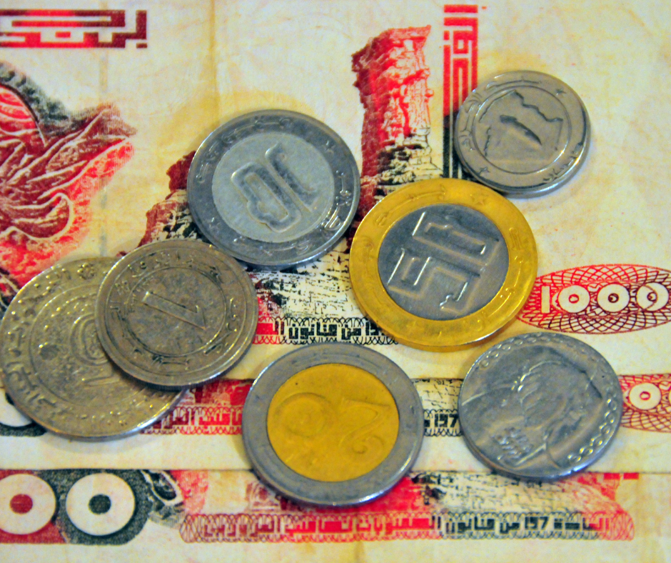 Algerian dinar coins spread over a banknote