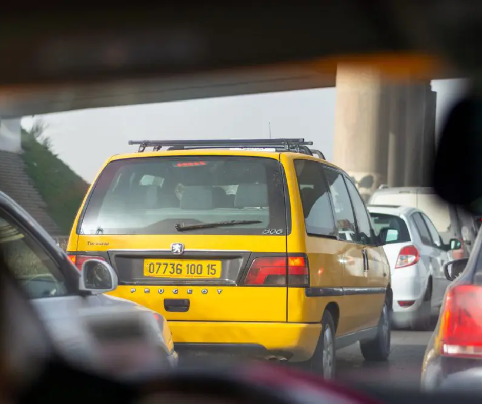 Yellow Peugeot taxi seen from inside a car in city traffic