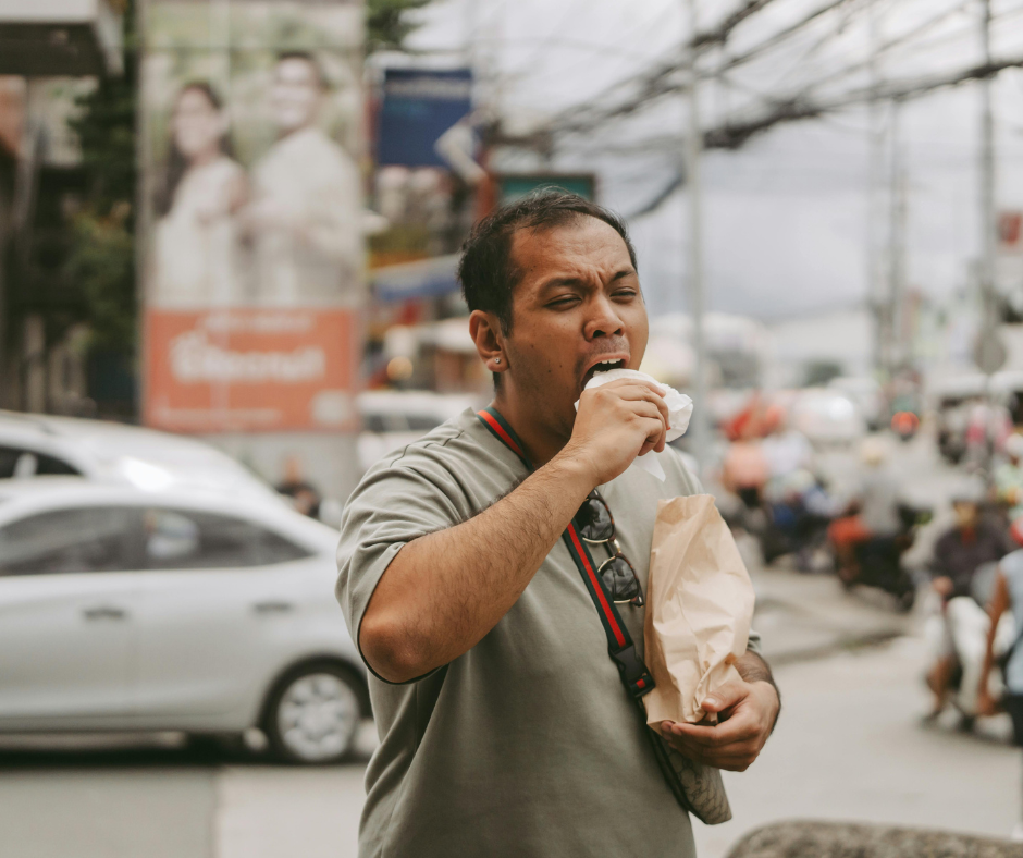 Man biting into a wrapped snack on a busy street