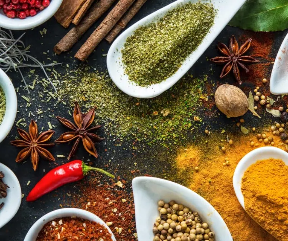 Colorful spices, star anise, cinnamon sticks and a red chili on a dark surface