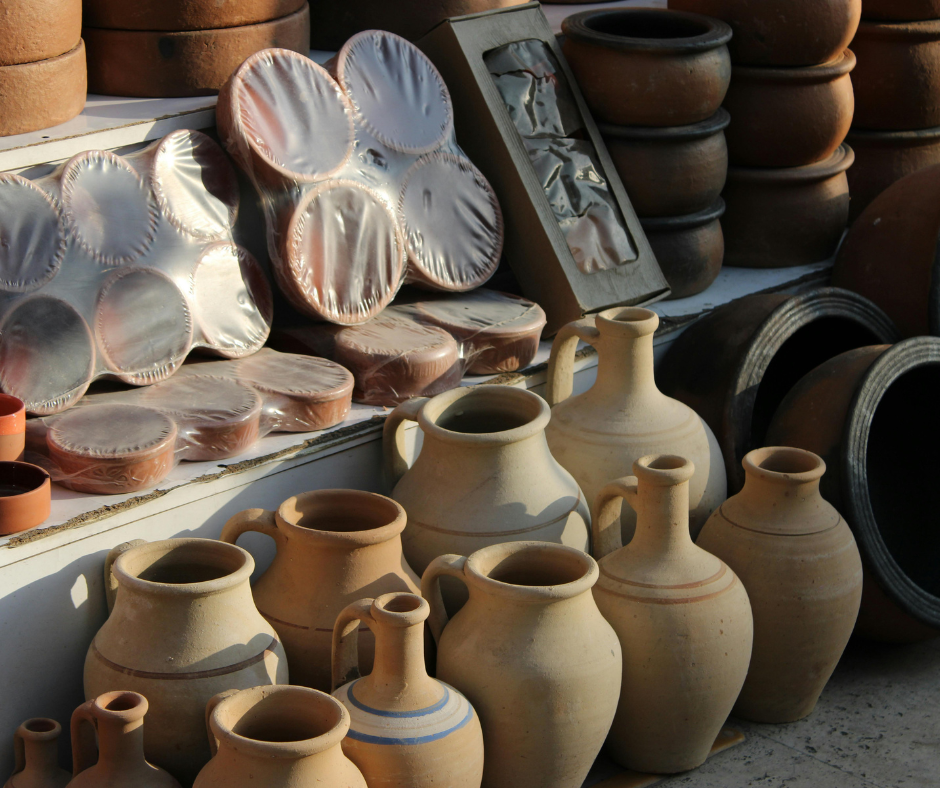Handmade clay jugs and pots stacked on a pottery stall