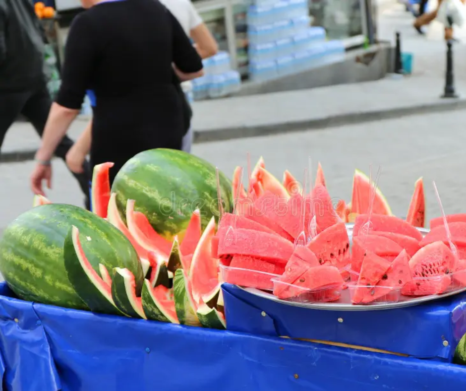 Cut watermelon slices and whole melons on a blue street stall