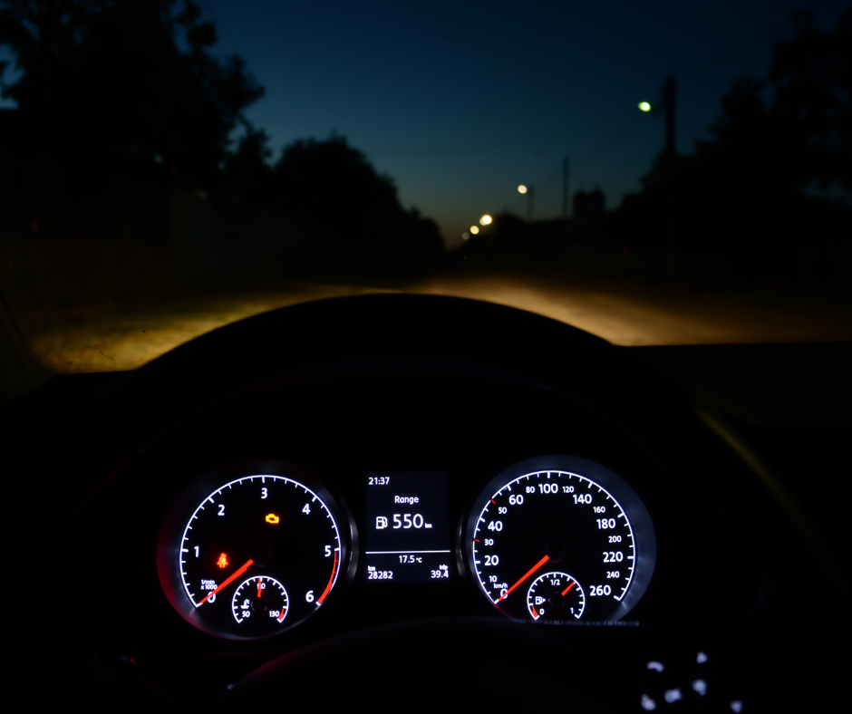 Car dashboard glowing at night on a dark road