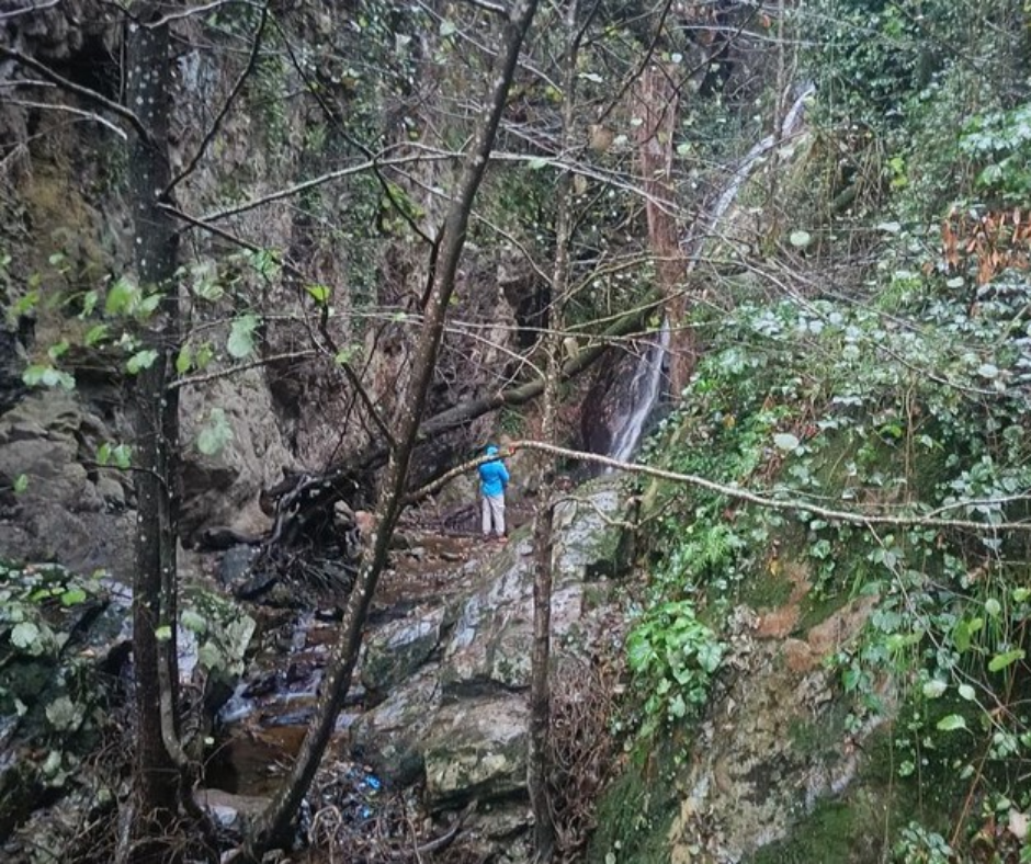 Hiker on a wet rocky trail beside a small waterfall in the Edough forest
