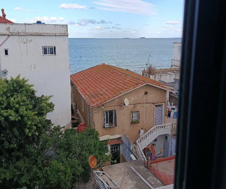 Sea view over red tile roofs and houses from a window