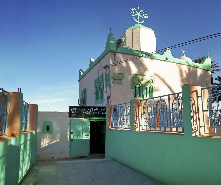 Small white and green marabout shrine with crescent finial and railings