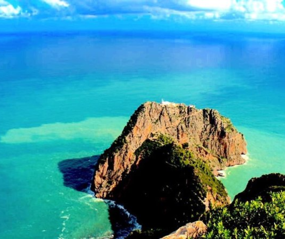 Rocky headland with a lighthouse over turquoise water at Cap Carbon