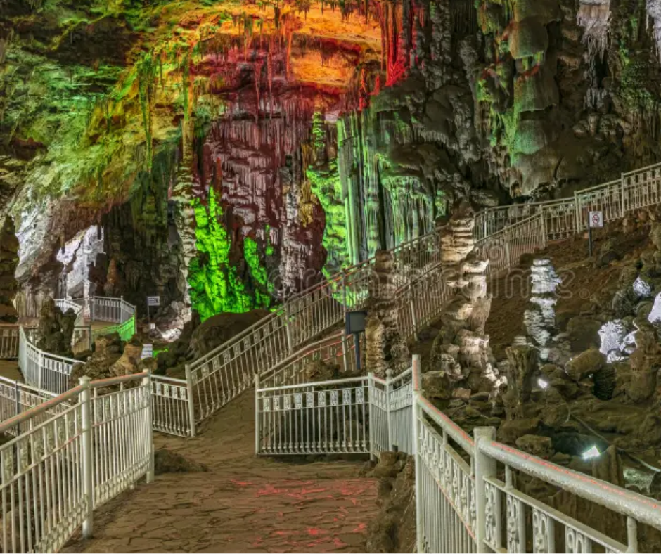Illuminated stalactite cave with white railings and walkways, Beni Add caves near Tlemcen