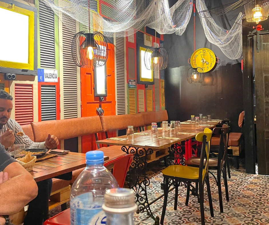 Casual restaurant with colorful shutter decor and wooden tables, a diner eating at left