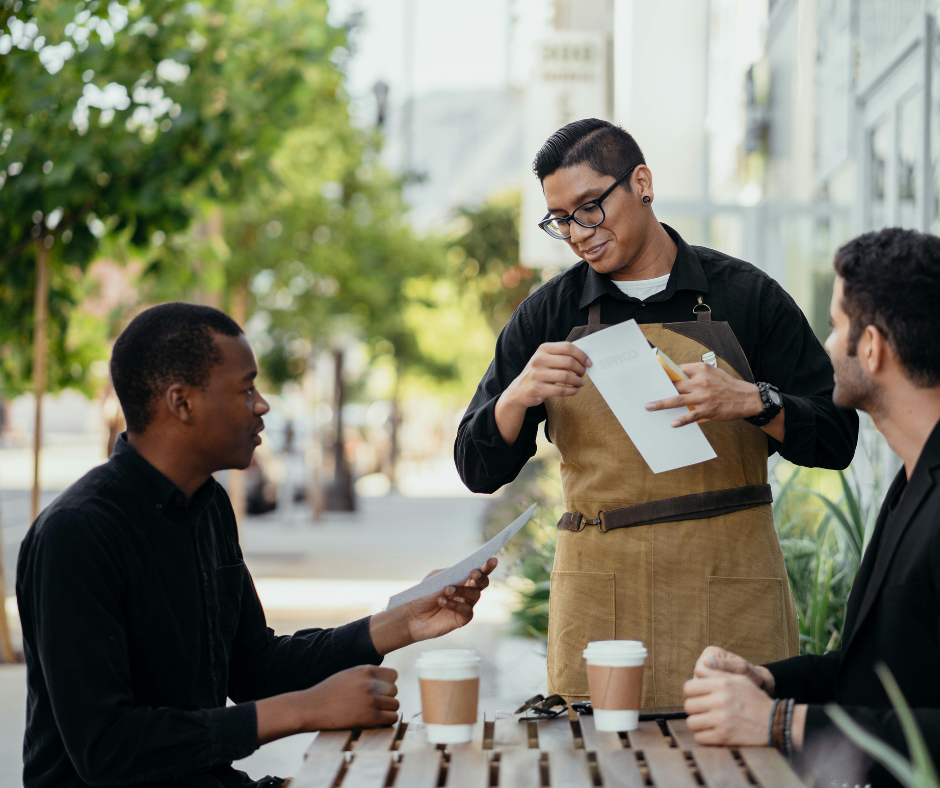 Waiter taking an order from two men at an outdoor cafe table