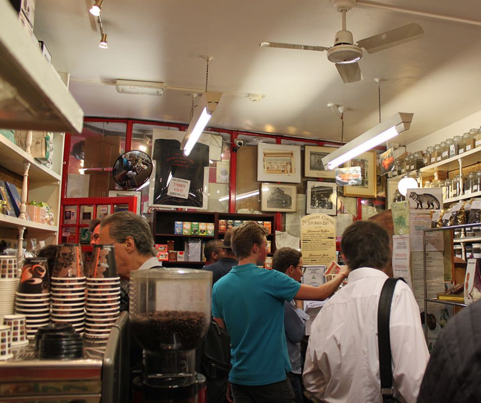 Crowded coffee shop counter with customers and a coffee grinder