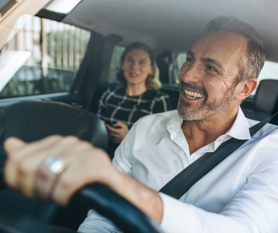 Smiling driver with a passenger behind him in a car