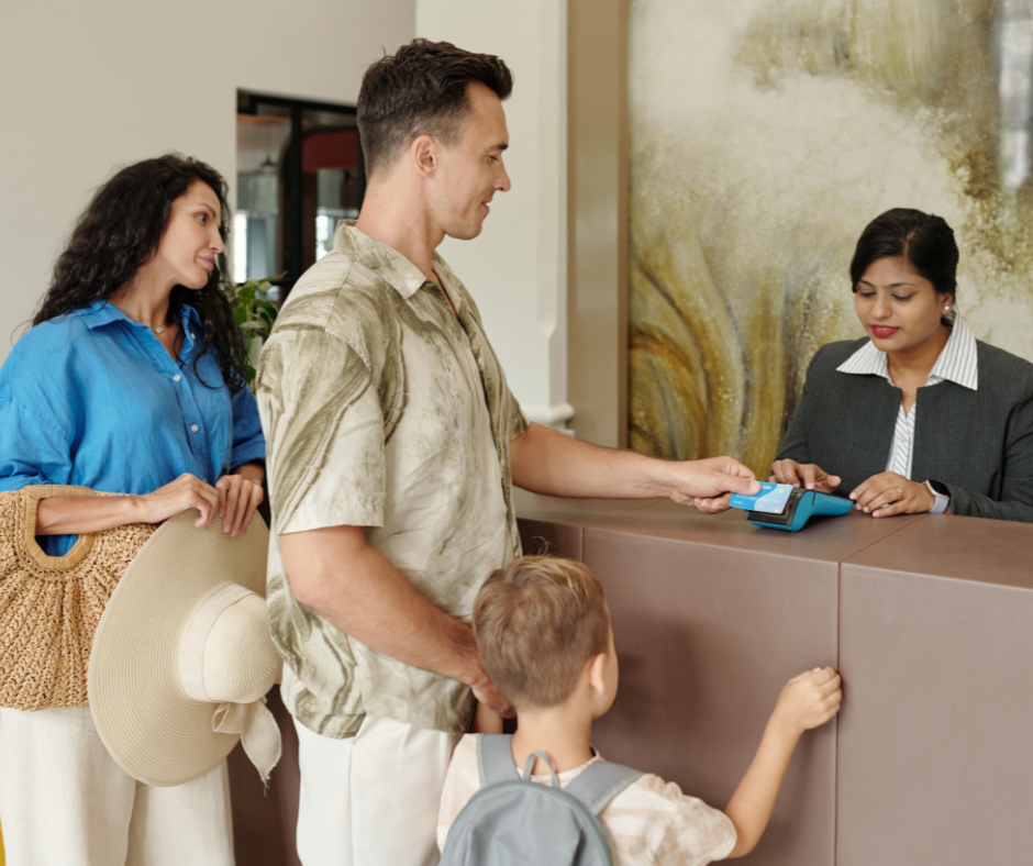 Family checking in at a hotel front desk and paying by card machine