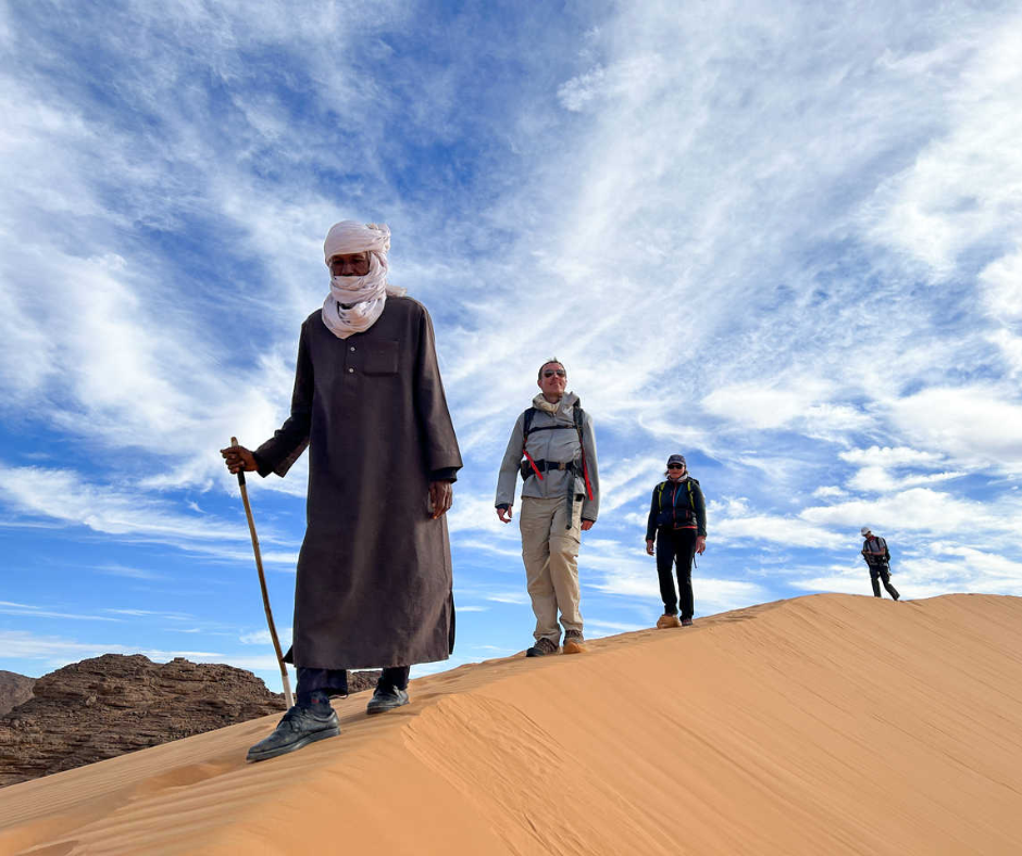 Tuareg guide leading hikers along a sand dune crest near Djanet