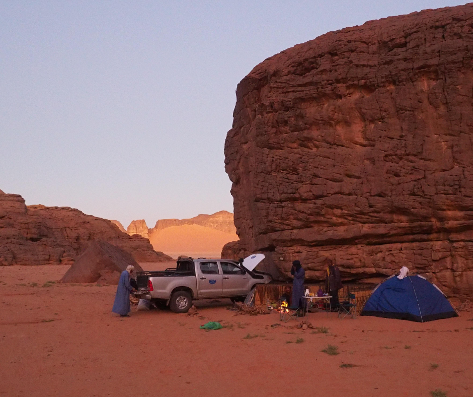Camp at the foot of a red sandstone cliff with a pickup and a blue tent