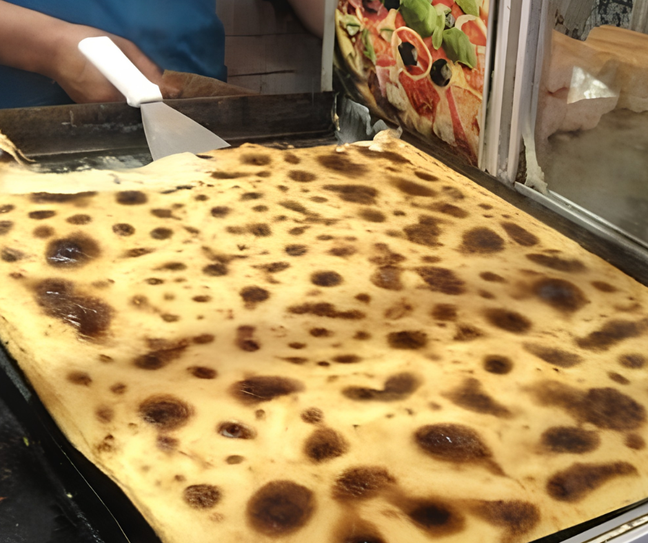 Large flatbread cooking on a griddle at a street food stall in Algiers