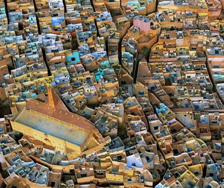 Aerial view of packed pastel M'Zab houses around a mosque with a pointed minaret