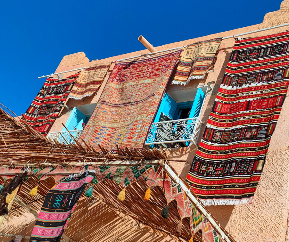 Colorful M'Zab carpets and rugs hung from a house facade and awning