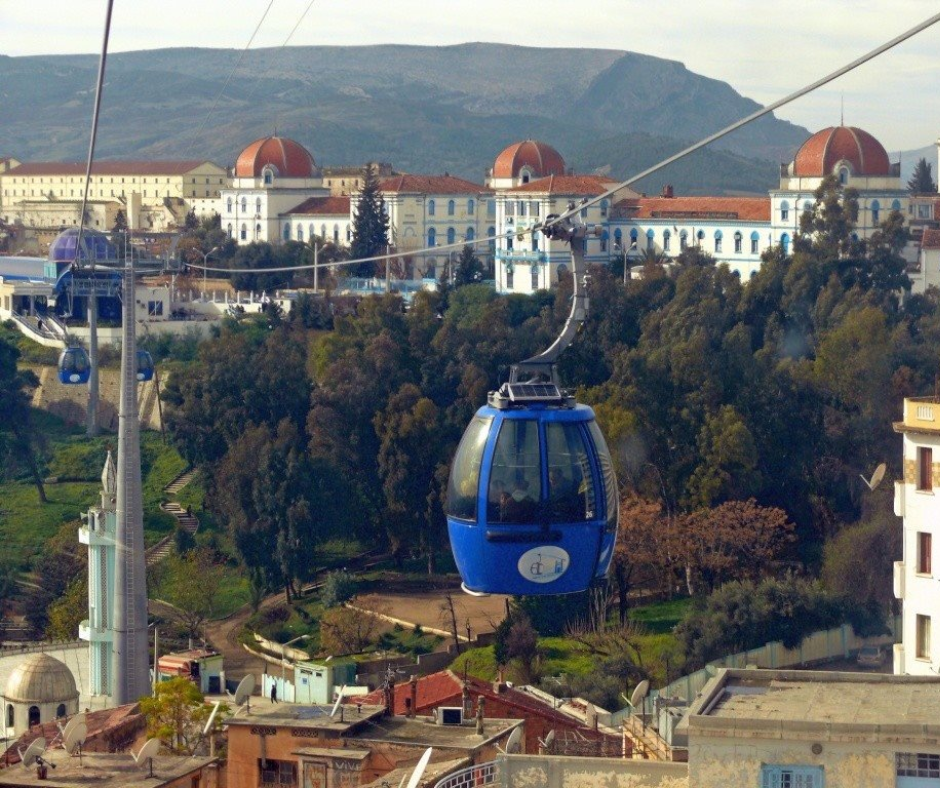 Blue cable car cabin over Constantine with domed buildings behind