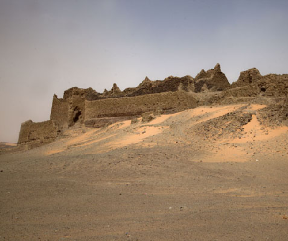 Ruined mud-brick fortress walls on a sand dune in the Sahara