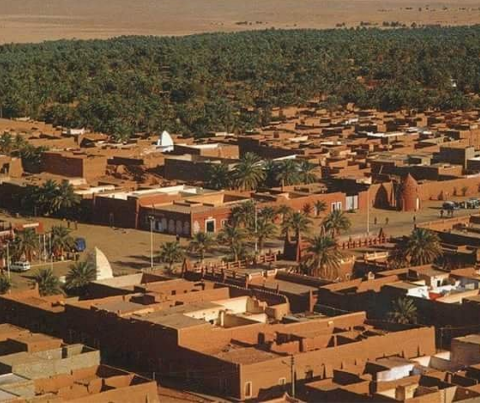 Aerial view of Timimoun's red mud-brick houses with palm groves behind