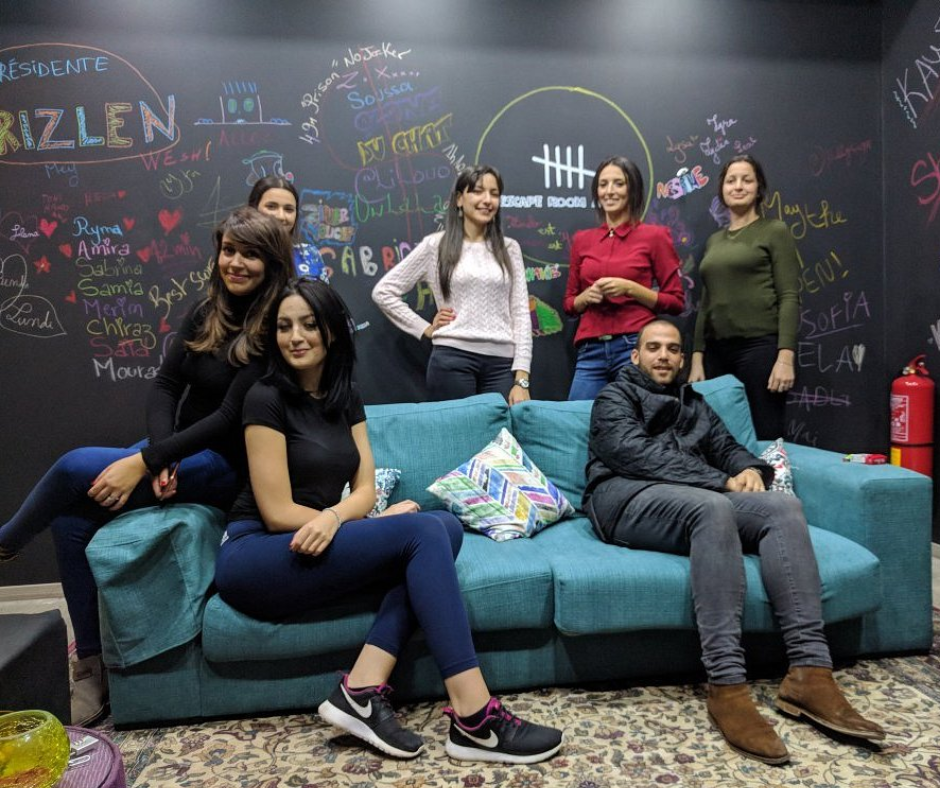 Young people posing on a sofa in front of a chalkboard wall in an escape room