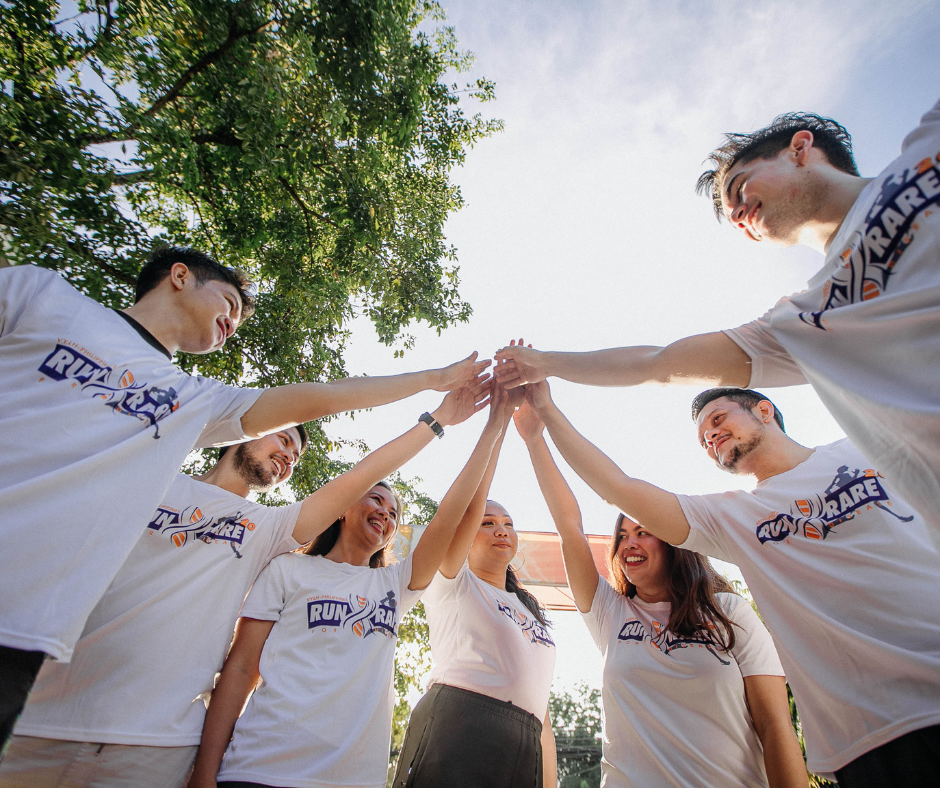 Group of colleagues joining hands in a circle under a tree