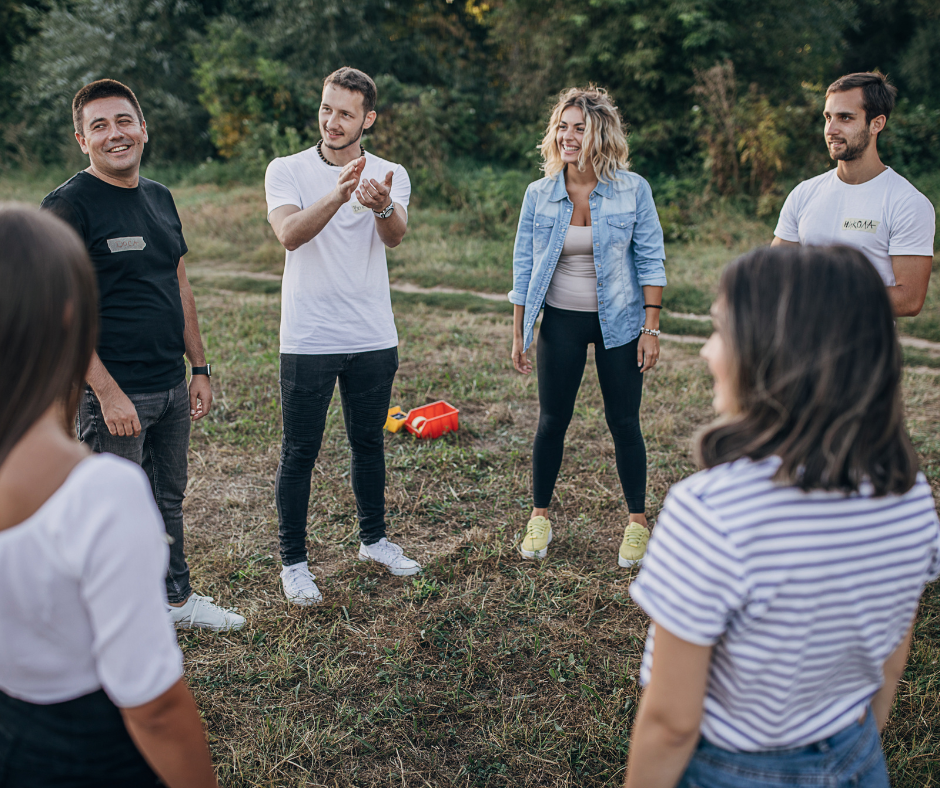 Colleagues standing in a circle on grass during a team activity