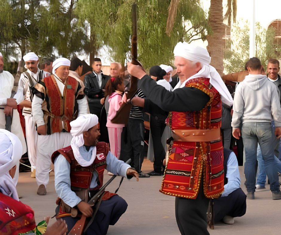 Men in red embroidered waistcoats and white turbans holding long rifles at a folk display