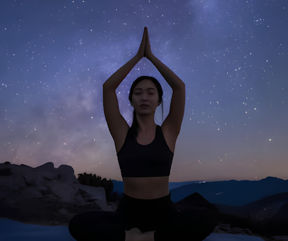 Woman practicing yoga with raised arms under a starry night sky